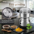Stainless steel spice grinder on a kitchen counter with ingredients and a blurred background